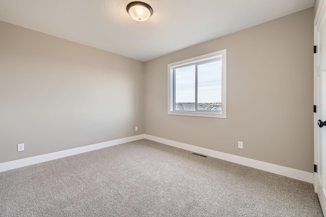 empty room with carpet flooring, visible vents, and baseboards