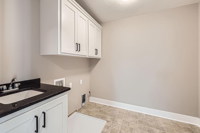 laundry area featuring baseboards, washer hookup, cabinet space, a textured ceiling, and a sink