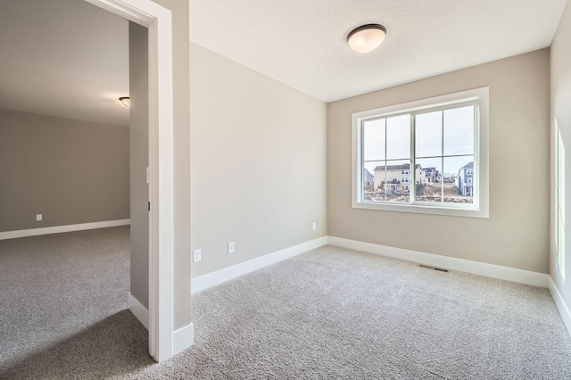 unfurnished room featuring visible vents, carpet flooring, and baseboards