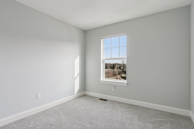 carpeted spare room with visible vents and baseboards