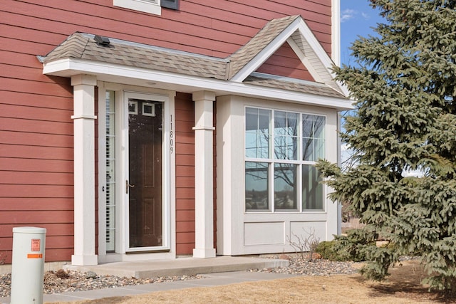 view of exterior entry with a shingled roof