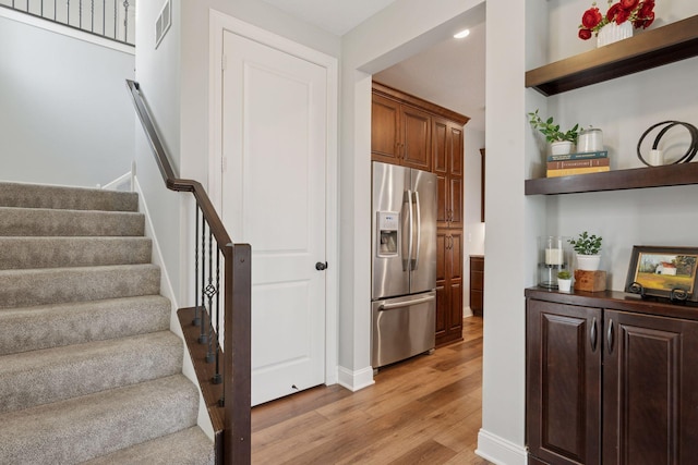 staircase featuring wood finished floors and visible vents