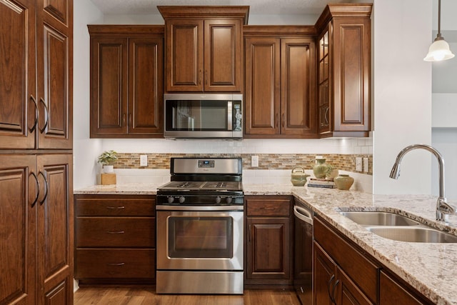 kitchen featuring a sink, stainless steel appliances, and light stone countertops