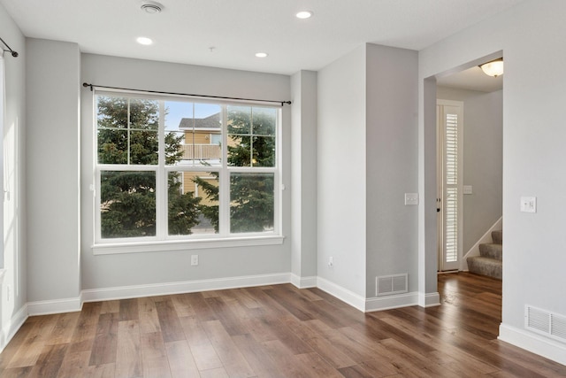 unfurnished room featuring wood finished floors, visible vents, and baseboards