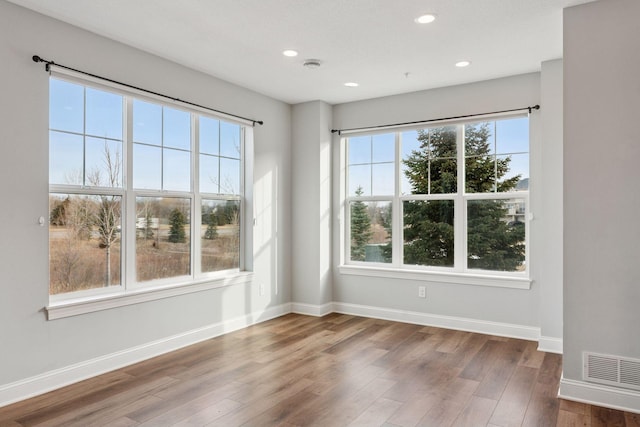 empty room featuring recessed lighting, baseboards, a healthy amount of sunlight, and wood finished floors