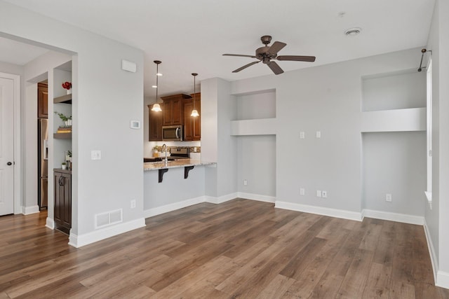 unfurnished living room featuring dark wood-type flooring, baseboards, visible vents, and ceiling fan