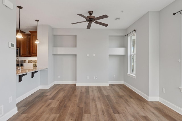 unfurnished living room featuring ceiling fan, baseboards, and wood finished floors