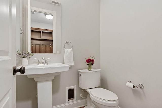 half bath featuring visible vents, toilet, and baseboards