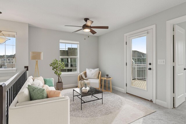 living area with a ceiling fan, baseboards, and carpet floors