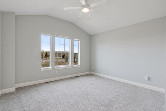 carpeted spare room featuring baseboards, a ceiling fan, and vaulted ceiling