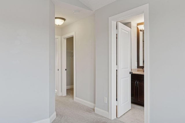 hall featuring baseboards and light carpet