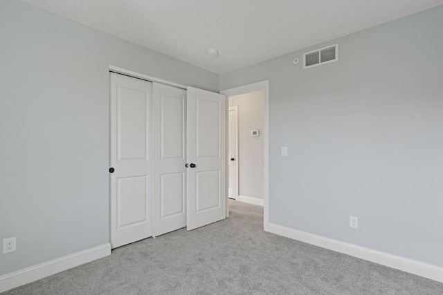 unfurnished bedroom featuring carpet flooring, baseboards, visible vents, and a closet