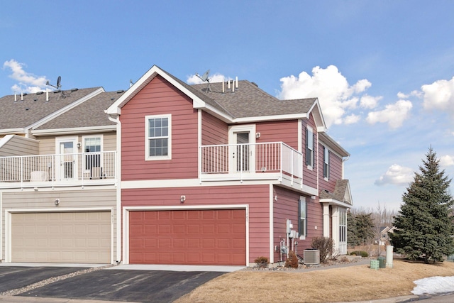 view of front of house with a garage, driveway, a shingled roof, and a balcony