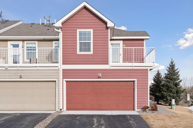 townhome / multi-family property featuring a balcony, an attached garage, driveway, and a shingled roof