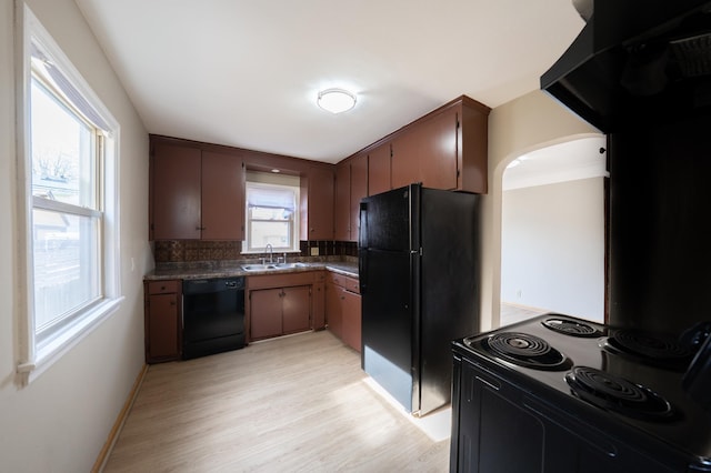 kitchen with dark countertops, decorative backsplash, light wood-style flooring, black appliances, and a sink