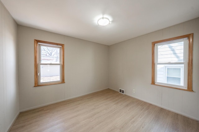 empty room featuring baseboards, visible vents, and light wood-type flooring