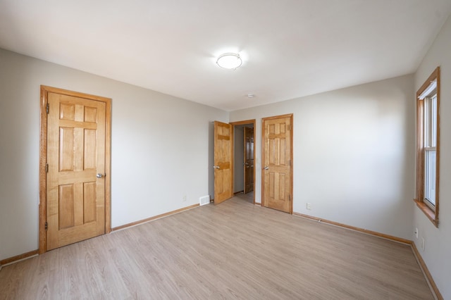 unfurnished bedroom featuring visible vents, baseboards, and light wood-style floors