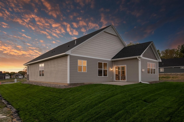 back of house featuring board and batten siding, a patio area, and a lawn