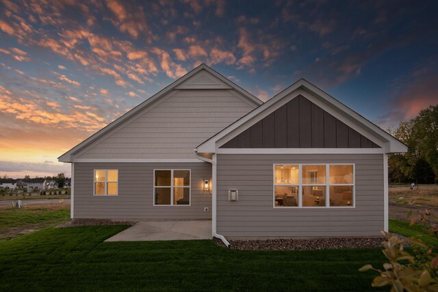 back of house featuring a yard, a patio area, and board and batten siding