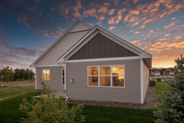 view of side of home featuring central AC unit, a lawn, and board and batten siding