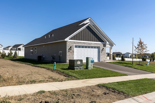 view of side of property with driveway, stone siding, a yard, board and batten siding, and central AC unit