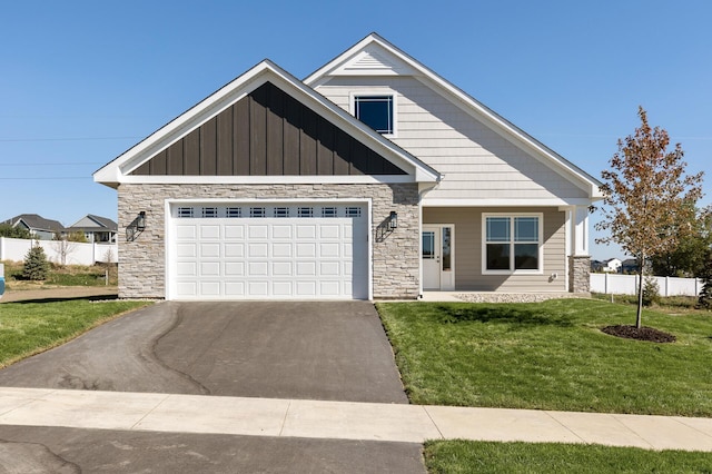 view of front of house featuring a front yard, fence, stone siding, and driveway