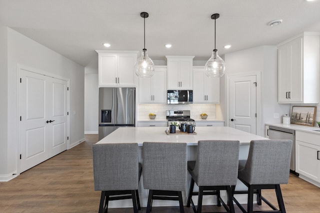 kitchen featuring stainless steel appliances, wood finished floors, a center island, and white cabinets