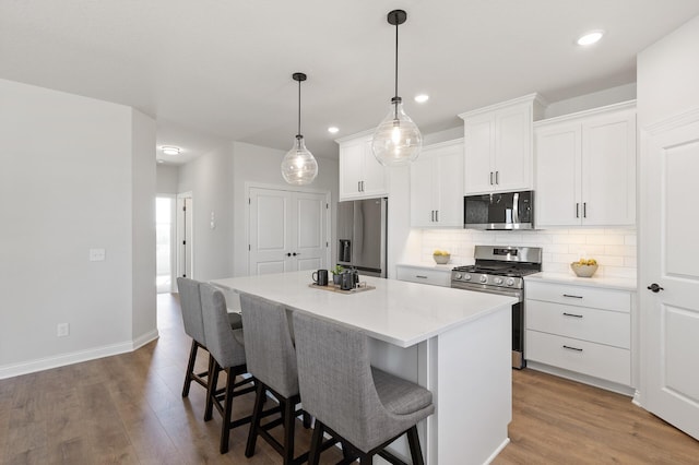 kitchen with decorative backsplash, wood finished floors, appliances with stainless steel finishes, and a kitchen island