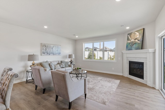 living room featuring recessed lighting, baseboards, a brick fireplace, and wood finished floors