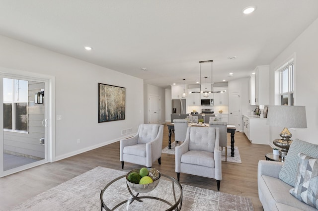 living area featuring visible vents, recessed lighting, baseboards, and light wood-style floors