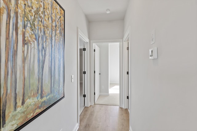 hallway featuring baseboards and light wood-style floors