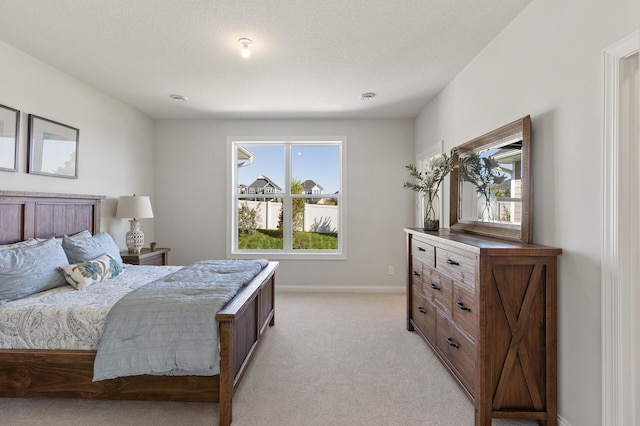 bedroom featuring light colored carpet, a textured ceiling, and baseboards