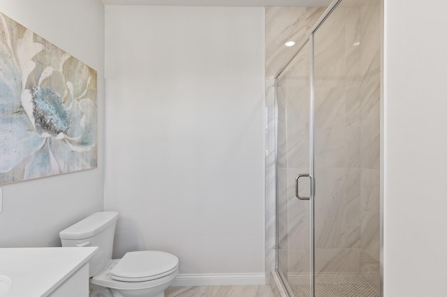 bathroom with baseboards, a shower stall, vanity, and toilet