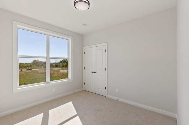 unfurnished room featuring baseboards and light colored carpet