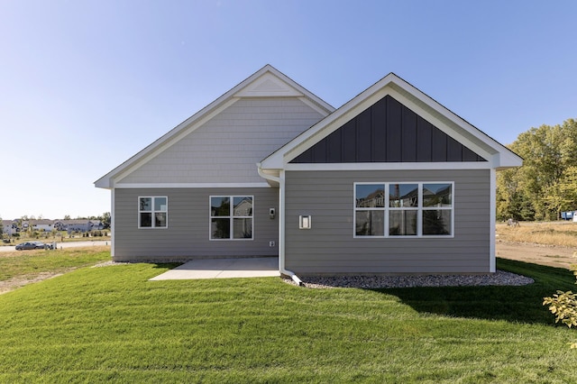 rear view of property featuring a yard, a patio, and board and batten siding