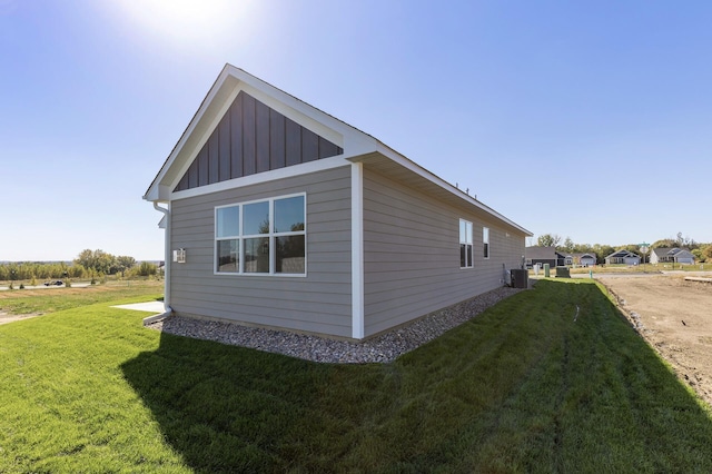 view of home's exterior with cooling unit, a lawn, and board and batten siding