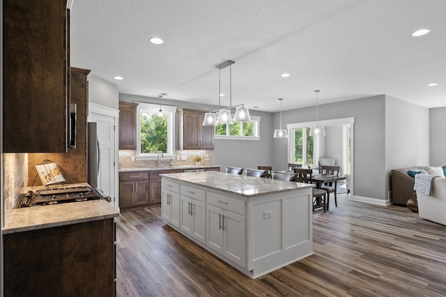 kitchen with tasteful backsplash, dark wood finished floors, a center island, and hanging light fixtures