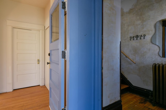 corridor featuring radiator and wood finished floors