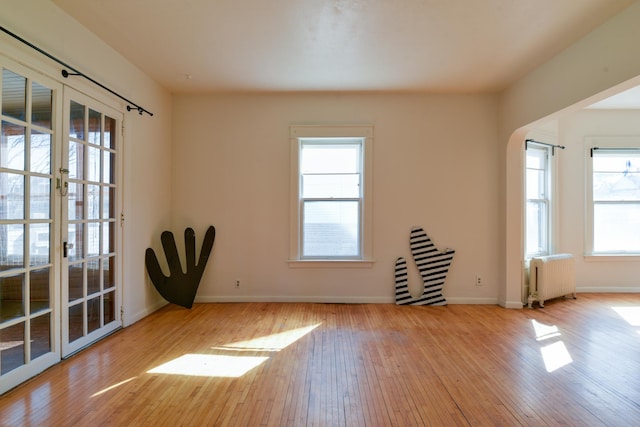 unfurnished room with hardwood / wood-style flooring, radiator, and baseboards