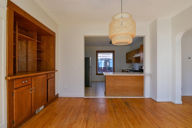 kitchen with visible vents, brown cabinetry, light wood-style flooring, appliances with stainless steel finishes, and arched walkways