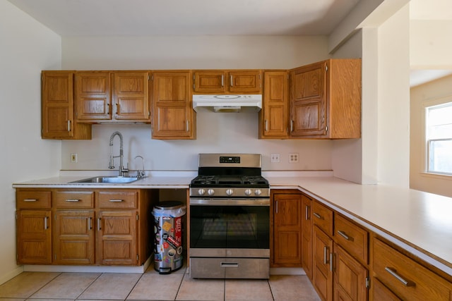 kitchen featuring gas stove, a sink, light countertops, under cabinet range hood, and brown cabinets