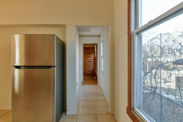 hallway with light tile patterned floors and baseboards