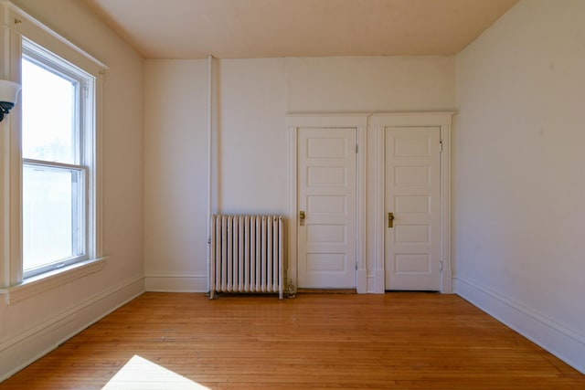 spare room with a healthy amount of sunlight, radiator, baseboards, and light wood-style floors