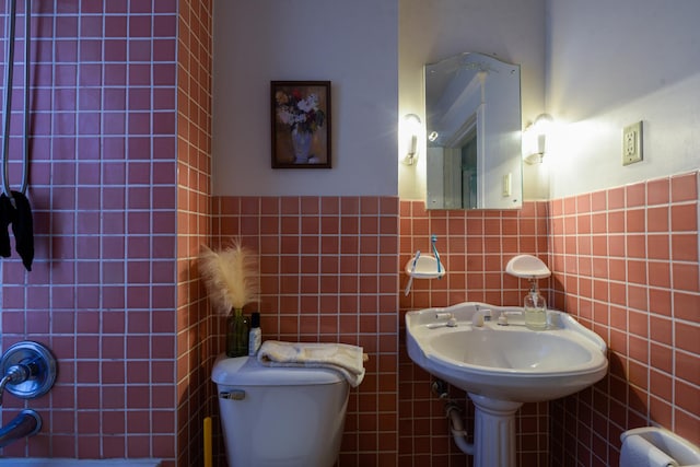 bathroom with bathing tub / shower combination, toilet, tile walls, and wainscoting