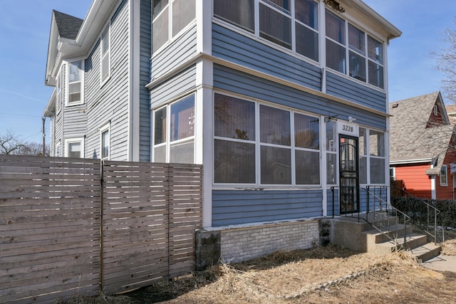 view of property exterior featuring fence and a sunroom