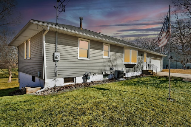 back of property with a garage, a lawn, central AC, and concrete driveway