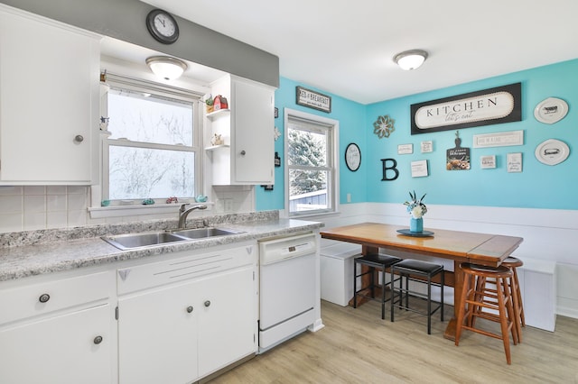 kitchen with light wood finished floors, white cabinetry, a sink, light countertops, and dishwasher