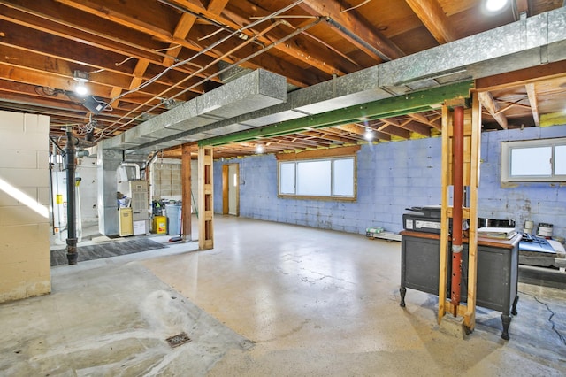 below grade area with gas water heater, heating unit, and concrete block wall