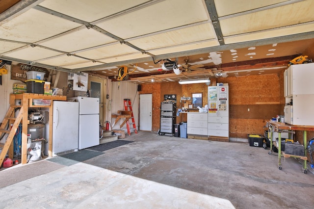 garage with a workshop area, a garage door opener, and freestanding refrigerator