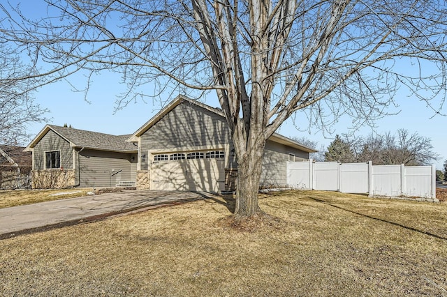 view of front of house featuring a front lawn, fence, a garage, and driveway